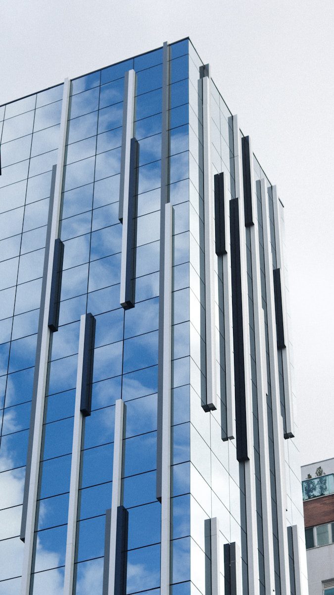 Futuristic urban skyscrapers with glass facades reflecting a vibrant blue sky.
